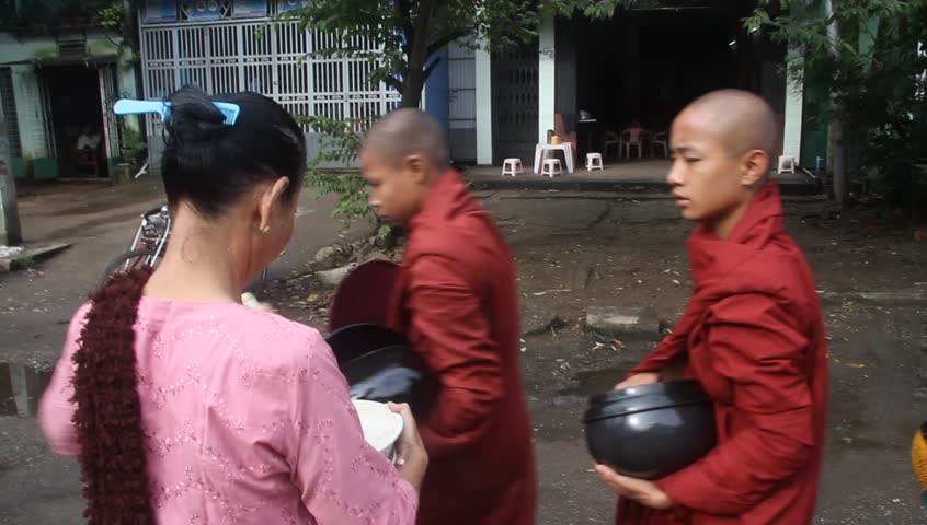 YANGON, MYANMAR - 18 AUGUST 2011 - Buddhist monks receive food from local women circa August 18, 2011, Yangon, Myanmar. 