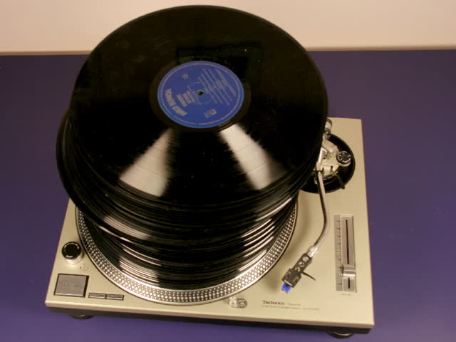 vinyl records being piled high on a turntable