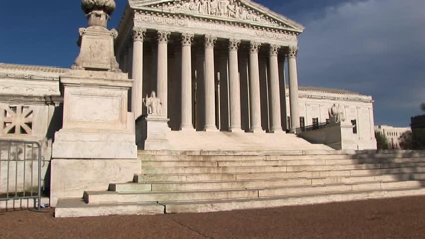 Sunlight reflects on the white stone steps and bright white pillars of the U.S. Supreme Court Building entrance.