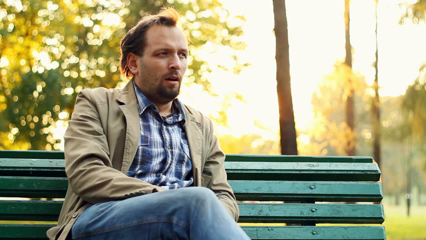 Sick man on park bench coughing