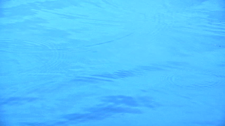 Water drops hitting an expanse of very blue water
