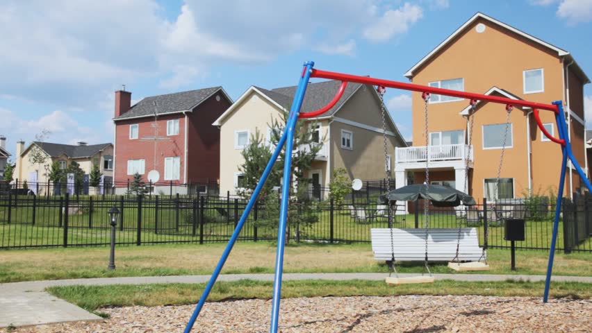 childrens playground with swing against big country houses