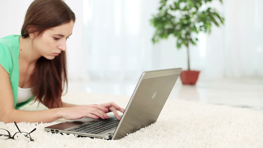 Young adult offended by lying on the carpet with laptop. DOLLY HD 