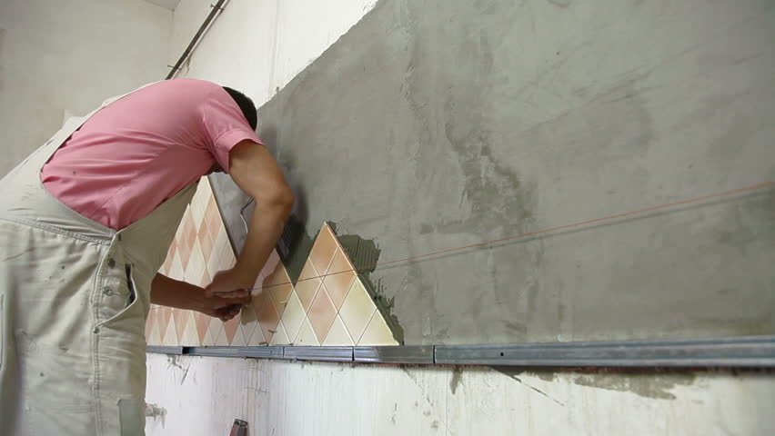 Man applying ceramic tile to a Kitchen wall