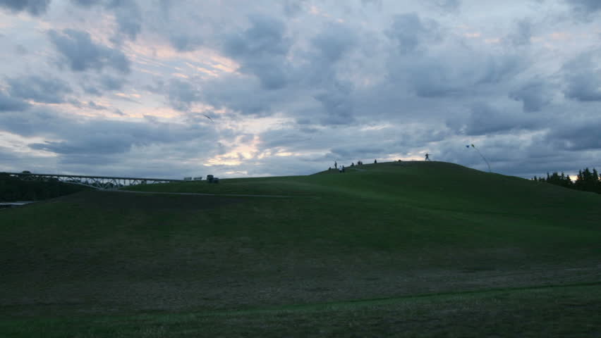 Clouds and people move across the sky behind a landfill