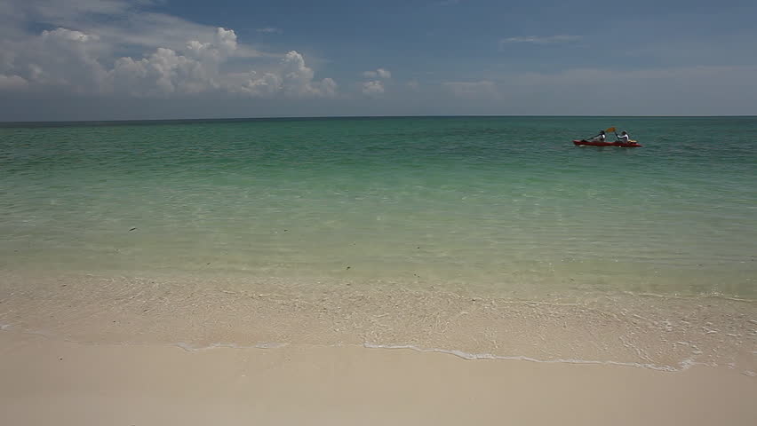 Sea with waves and two unrecognizable persons rowing in a kayak