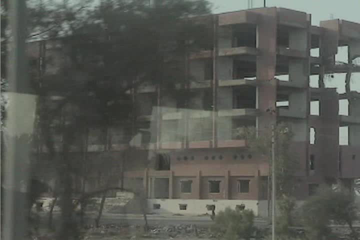 A point of view from a moving vehicle of buildings bombed and destroyed in the Iraq war.