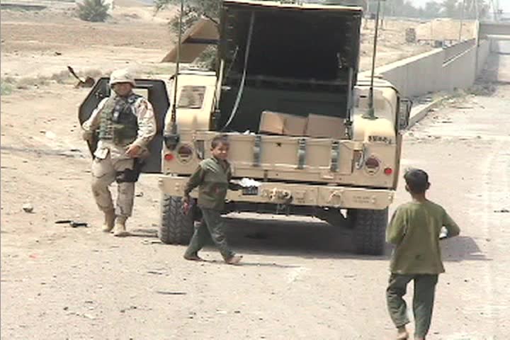 BAGHDAD, IRAQ - CIRCA 2009: An American soldier hands out toys and other gifts to a young Iraqi boy.