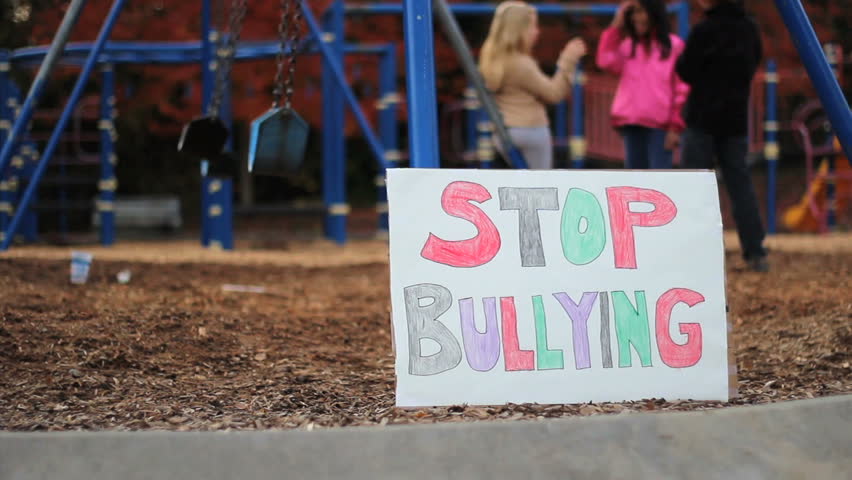A group of students stand behind a "stop bullying" sign on the school playground serving as a reminder for everyone.