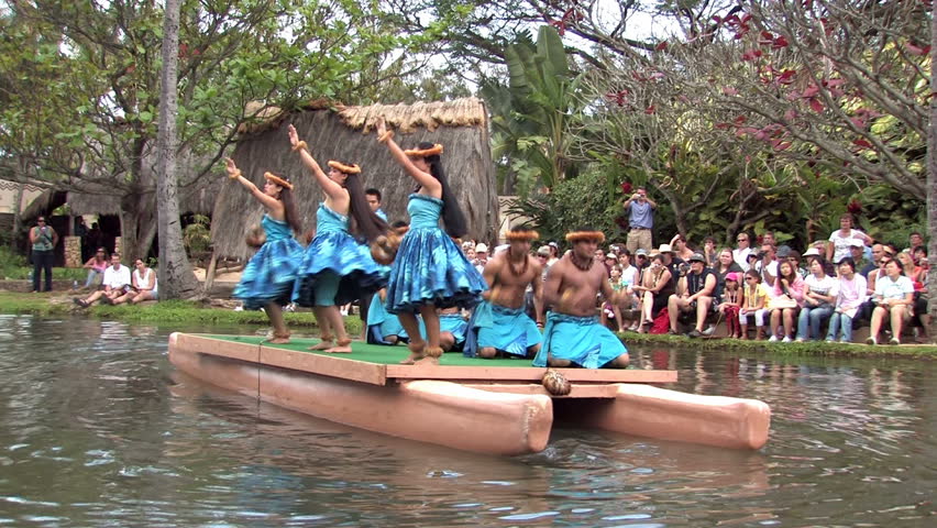 Polynesian Cultural Center in Laie Oahu Hawaii. Canoe show with dancers from Hawaii. Tourists on the main lagoon. Blue skirts on beautiful dancers. Water, lagoon and palm trees.