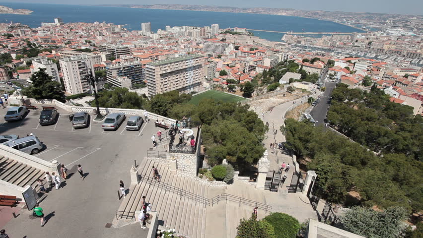 Tourists walking at Notre Dame de la Garde Cathedral view across city and Mediterranean Sea. Marseille France May 23 2011.
