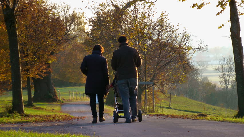 family with baby buggy strolling through the park