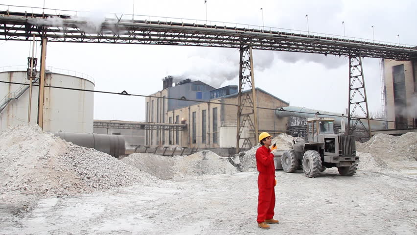 Industrial exterior with bulldozer. Industrial worker supervising the work of the bulldozer in the factory. HD 1080i.