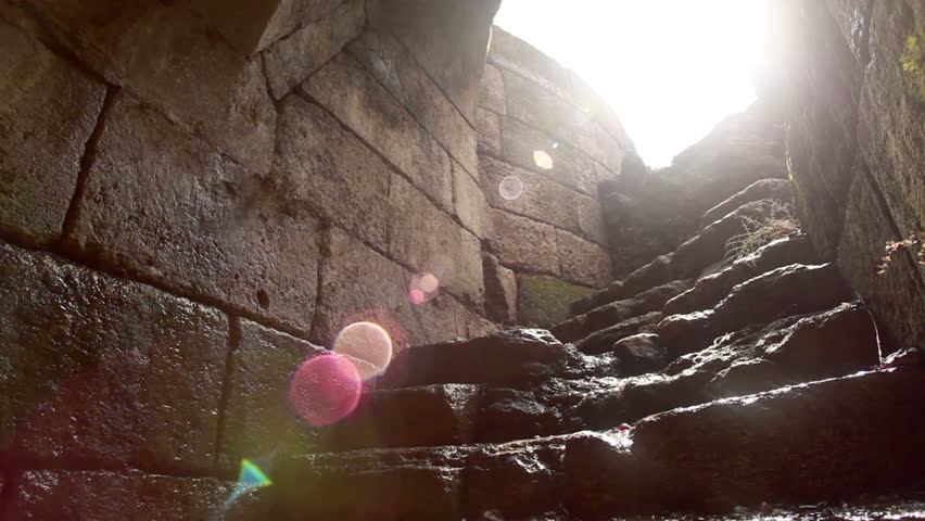 Slider dolly move right to left at the foot of a stone, curved stairway leading out of an underground passageway at the Antipas/Agrippa palace ruin in Israel. 