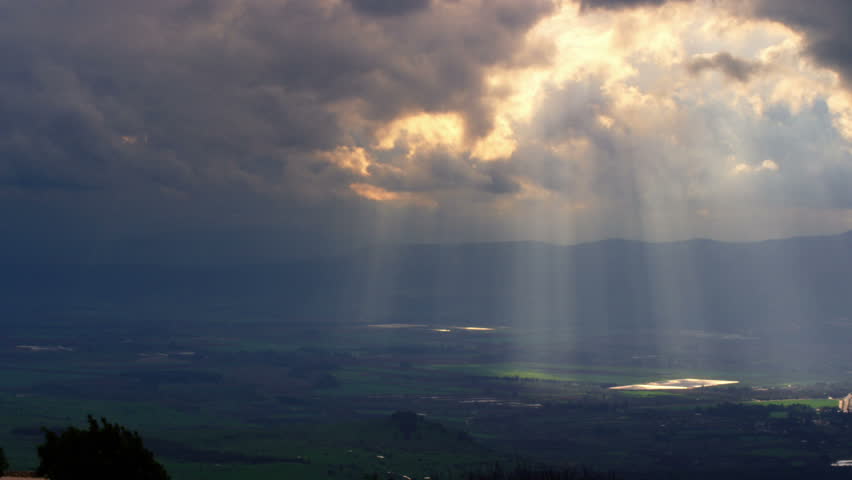 Pan of a beautiful, wide shot overlooking a valley below with awesome clouds with the sunbeams streaking across the whole valley. Taken from Nimrod Fortress in the Golan Heights, Israel. 02/21/2011