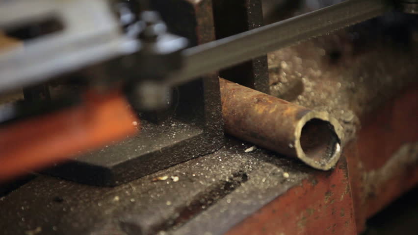 Cutting a hard steel pipe held in vise by heavy duty band saw. Industrial manufacture. Fast motion.