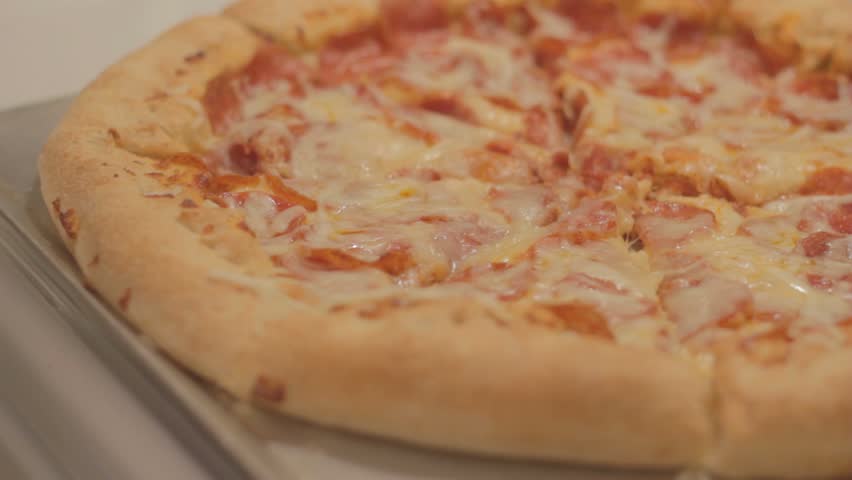 Slice of pepperoni pizza is pulled from a pie, then another