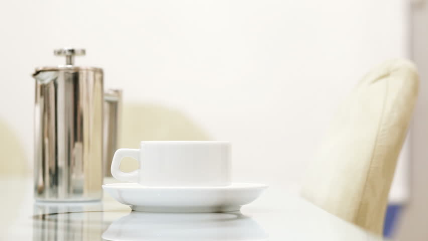 The waiter in the cafe pours tea into a cup. Pouring tea cup.