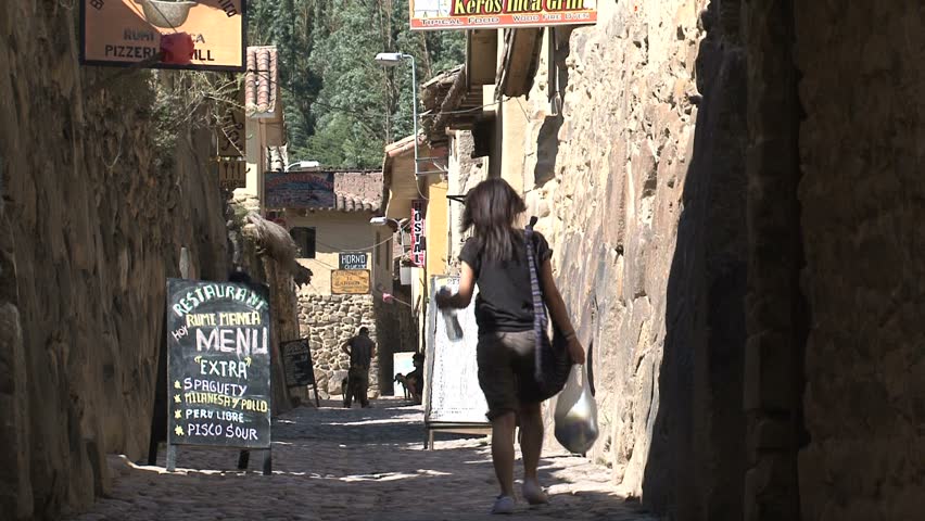 People walk down an alley with restaurants in Ollantaytambo