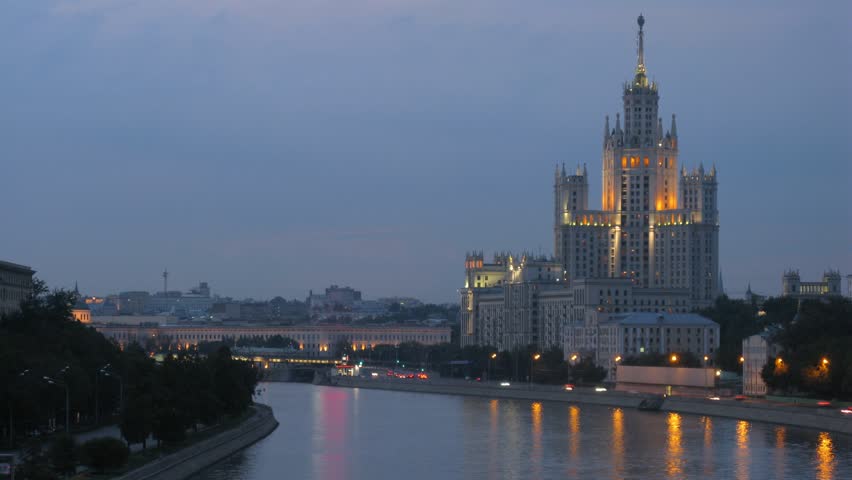 Inhabited skyscraper stands on Kotelnichesky quay near to road in evening, time lapse