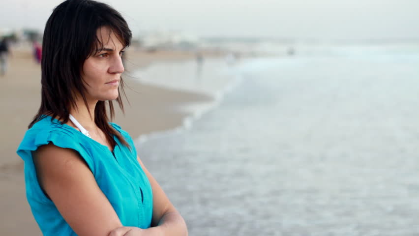 Sad pensive woman standing on the beach, camera stabilizer shot