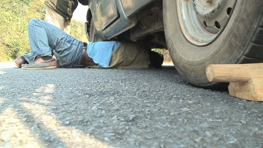 LUANG PRABANG, LAOS - January 14, 2007:  Working Underneath Car