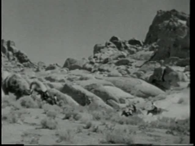 Men on horseback riding through mountain range