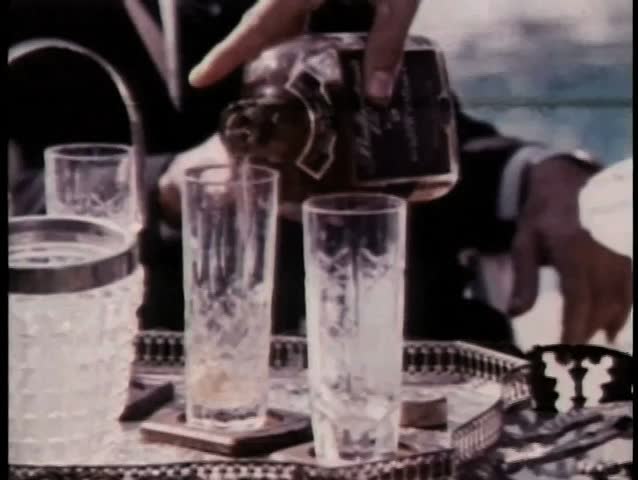 Close-up hand pouring liquor into glass and serving