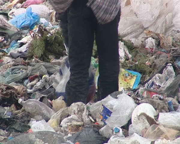 Homeless destitute men looking for food and useful items between them. Environmental pollution. Poverty. 