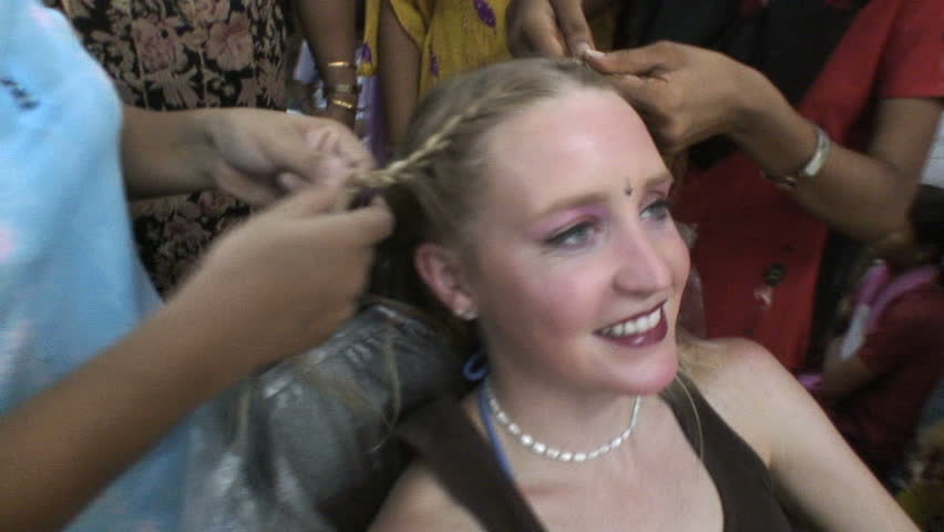 NEW DELHI, INDIA - AUGUST 31, 2007:  Hindu Women braid a western Touist's hair in a traditional way. 