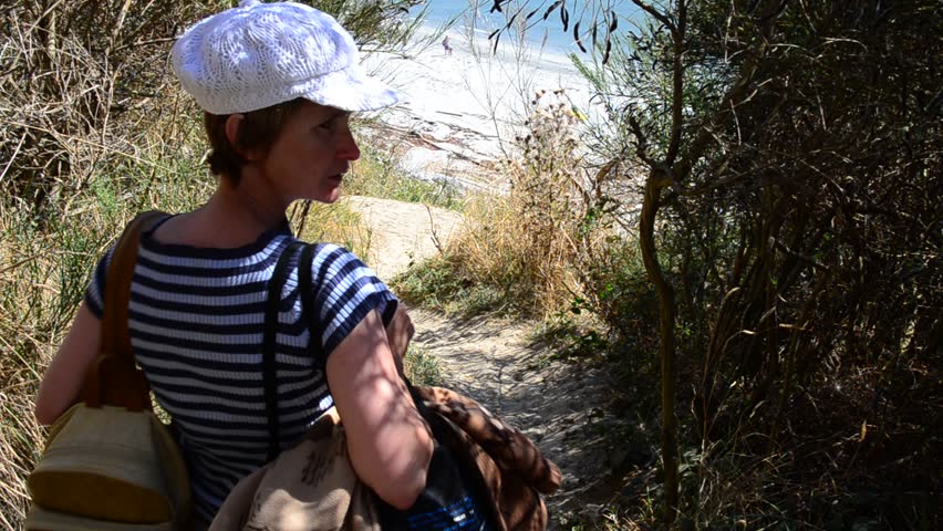 Middle age woman on sandy trail with nice ocean view at summer day in Vancouver, Canada.