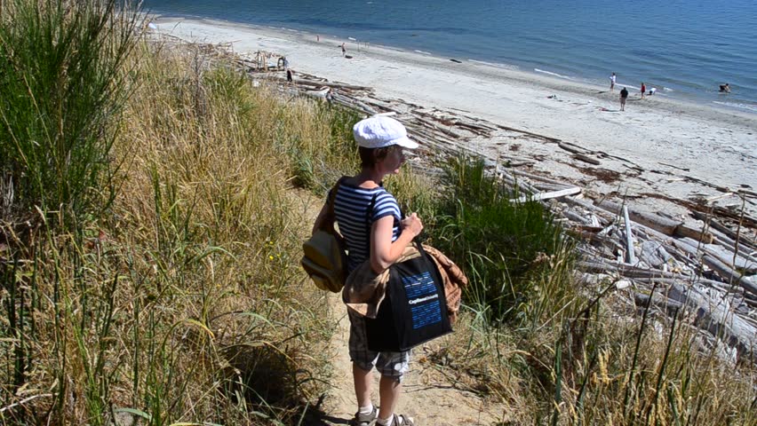 Middle age woman on sandy trail with nice ocean view at summer day in Vancouver, Canada.