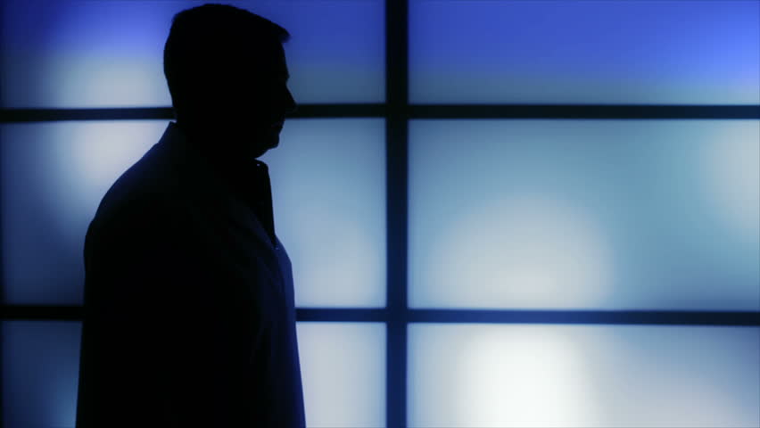 Silhouetted images of a nurse who enters the room and hands a physician his stethoscope and some paperwork for signature.