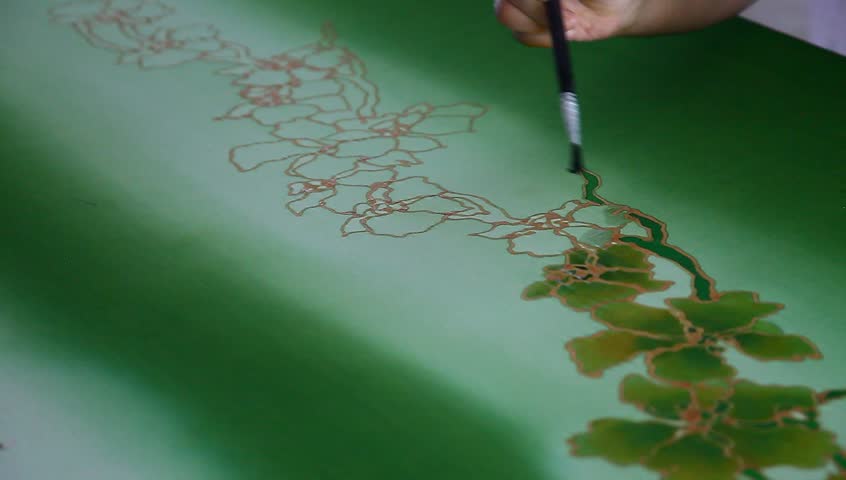 An artist coloring the batik fabric with floral motif