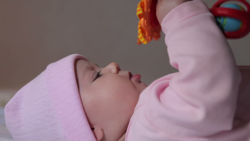 Baby wearing a pink hat chews toy