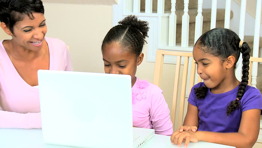 Cute african american girls using a laptop and watched by proud parent