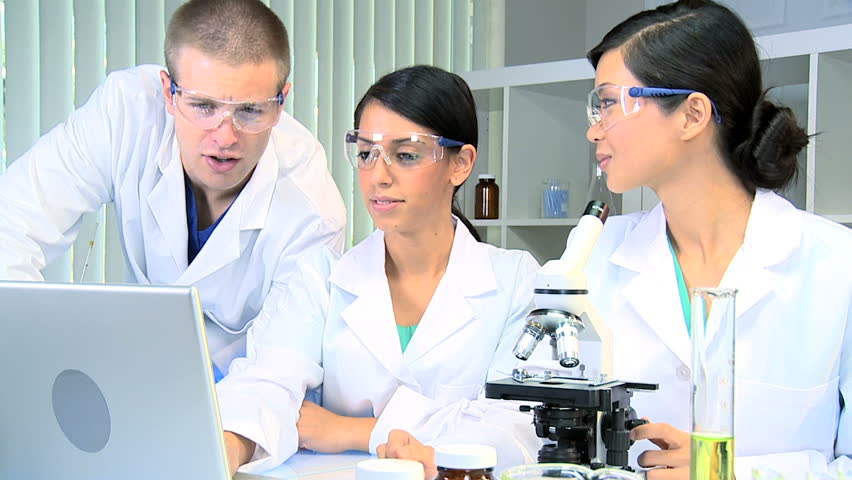 Caucasian doctor with two medical research students using computer technology in laboratory conditions
