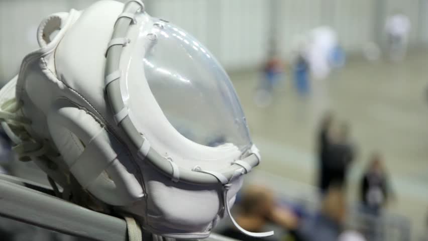 White protective helmet of fighter KUDO against sportsmen training in hall