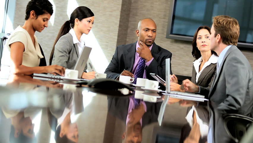 Team of five multi ethnic business people in city clothes meeting in a modern office boardroom