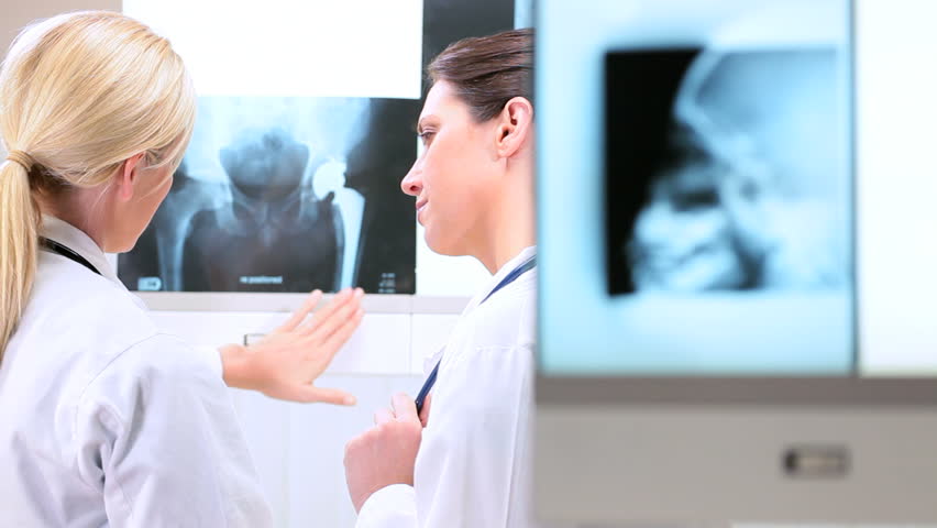Young female doctors in hospital radiology department inspecting x-rays