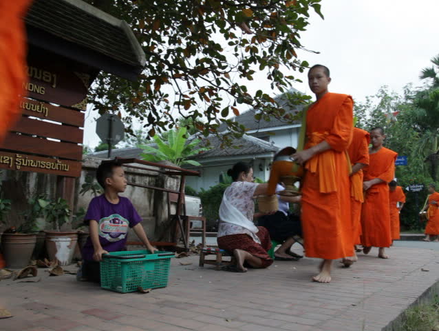 LUANG PRABANG, LAOS - OCTOBER 27: Two women give sticky rice to monks during the morning procession on October 27, 2011.