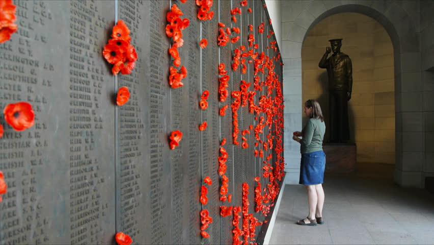CANBERRA, AUSTRALIA-CIRCA DECEMBER 2011: a visitor places a red poppy on the Honour Roll at the Australian War Memorial