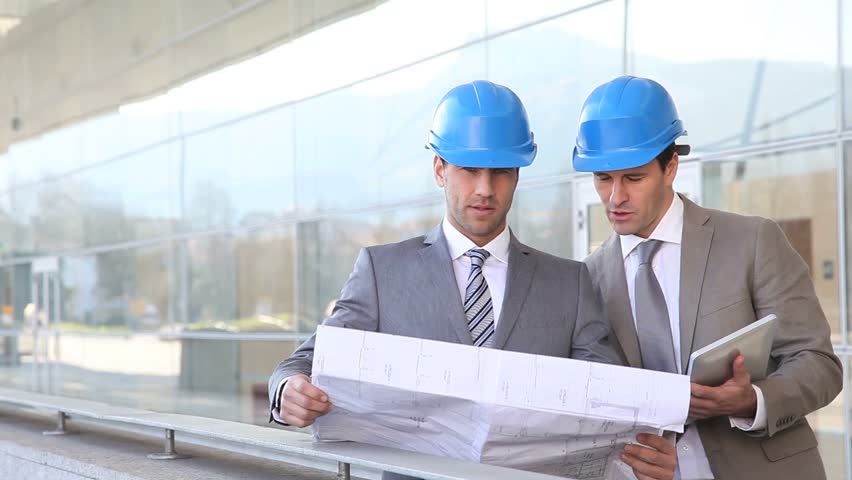 Architects checking construction site with plan outside