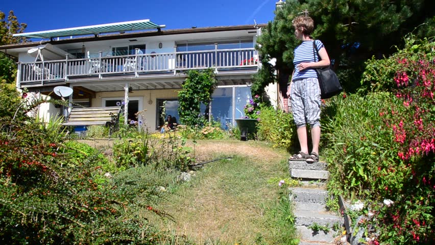 Middle age woman on trail with nice cottage view at summer day in Vancouver, Canada.