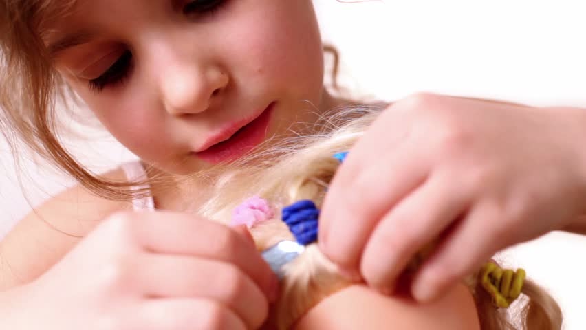 Little girl combs dolls hair