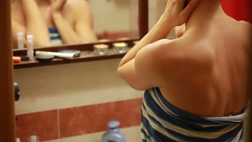 Woman caresses her skin in bathroom