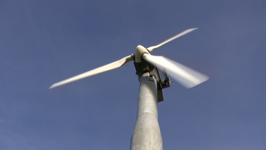 A wind turbine spins amidst a clear blue sky, delivering renewable and clean energy. (High Definition)