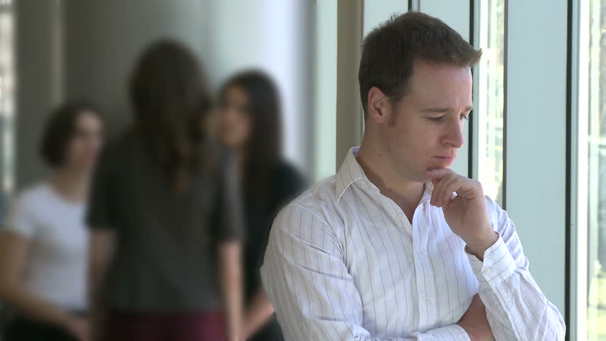 Male professional stands in front of coworkers - upset