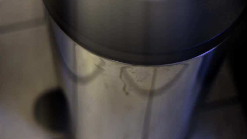 A foot opens the garbage can to throw trash away