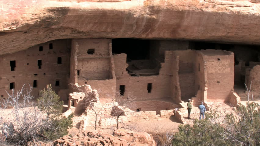 Mesa Verde National park southern Colorado. Spruce Tree ruins, tourists and ranger. Ancient Pueblo cliff buildings. Sheer cliff overhanging rocks and cave.  Historic Native American homeland heritage.